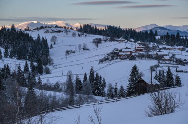 Voronenko, Carpathian, Ukrayna çevresindeki küçük Alp köyü ve kışın ilk gün doğumunda karlı dağlar..