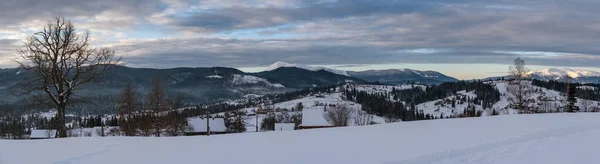 小さな高山の村と冬の雪の山の周りの最初の日の出の太陽の光で ボロネンコ カルパティア ウクライナ 雪のドリフトを介して新鮮な曲がりくねった道をトレース — ストック写真