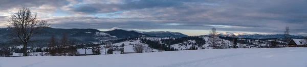 小さな高山の村と冬の雪の山の周りの最初の日の出の太陽の光で ボロネンコ カルパティア ウクライナ 雪のドリフトを介して新鮮な曲がりくねった道をトレース — ストック写真