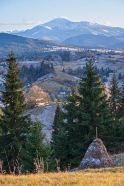 Sonbaharın sonlarında gün batımından önce, tepeleri karla kaplı bir dağ manzarası. Resimli seyahat, mevsimlik, doğa ve kırsal güzellik konsepti. Karpatlar, Ukrayna.