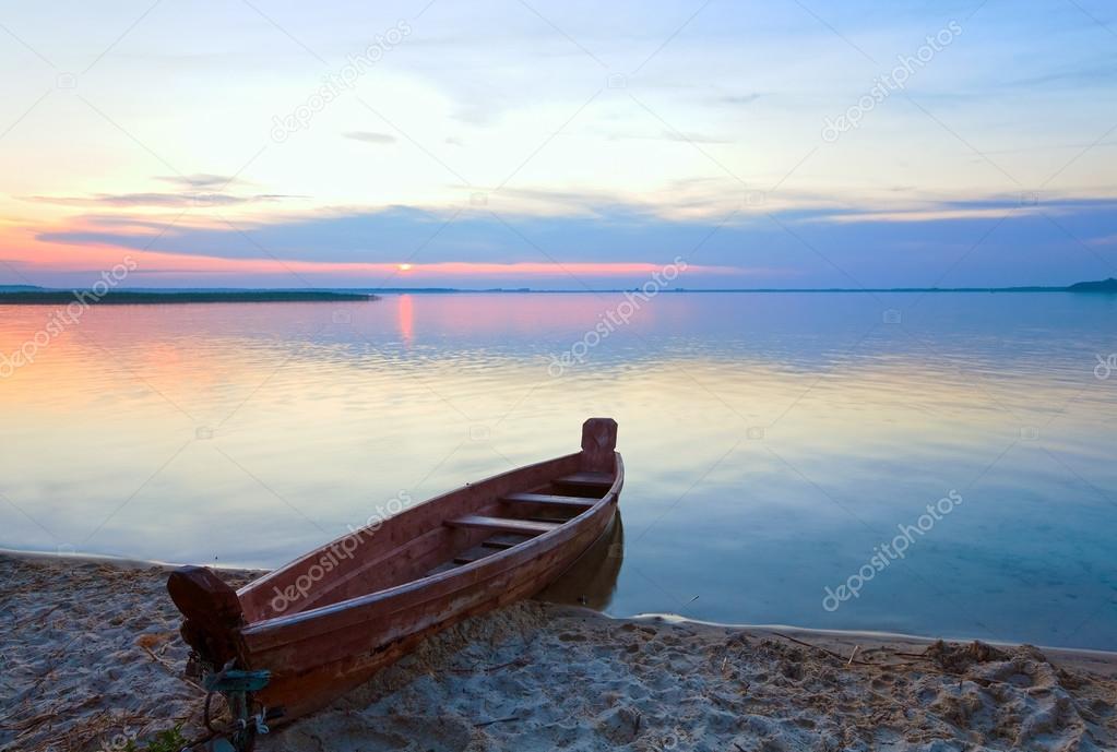 Sunset with boat near the summer lake shore