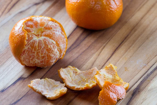 Laranja descascada em uma placa de corte — Fotografia de Stock