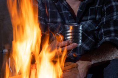 Ateşin yanında fasulye konservesi tutan eller.
