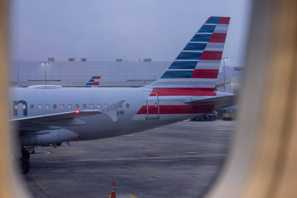 SAVANNAH, GEORGIA, USA, NOVEMBER 9, 2025: The tail and fuselage of a parked American Airlines jet, viewed through a passenger window just before departure, are visible on the tarmac at Savannah/Hilton Head International Airport (SAV).