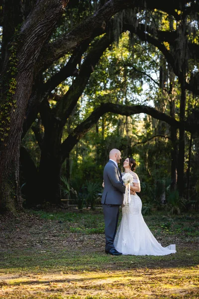 Güzel bir çiftin (gelin ve damat) İspanyol yosunlarıyla büyük meşe ağaçlarının altında evliliklerini kutlayan samimi ve zarif bir düğün portresi..