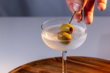 Zeytinleri toplayan el, temiz bir arkaplanda martini yapar.