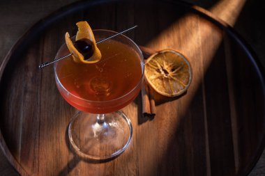 Negroni ya da Manhattan kokteylinin üzerinde kiraz ve portakal dilimleriyle servis edilen güzel bir ışıklandırma. Işık çarpıcı ve sıcak..