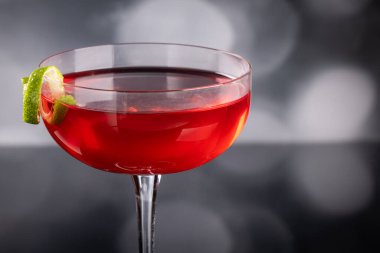 Güzel kozmopolit kokteyli limon kıvrımı ve dramatik ışıklandırmayla süslenmiş.