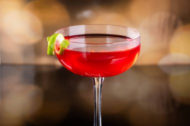 Güzel kozmopolit kokteyli limon kıvrımı ve dramatik ışıklandırmayla süslenmiş.