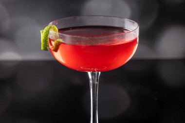 Güzel kozmopolit kokteyli limon kıvrımı ve dramatik ışıklandırmayla süslenmiş.