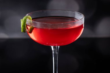 Güzel kozmopolit kokteyli limon kıvrımı ve dramatik ışıklandırmayla süslenmiş.