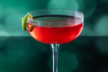 Güzel kozmopolit kokteyli limon kıvrımı ve dramatik ışıklandırmayla süslenmiş.