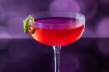 Güzel kozmopolit kokteyli limon kıvrımı ve dramatik ışıklandırmayla süslenmiş.