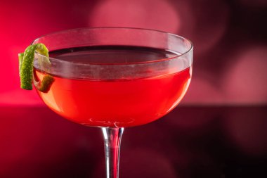 Güzel kozmopolit kokteyli limon kıvrımı ve dramatik ışıklandırmayla süslenmiş.