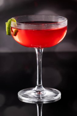 Güzel kozmopolit kokteyli limon kıvrımı ve dramatik ışıklandırmayla süslenmiş.