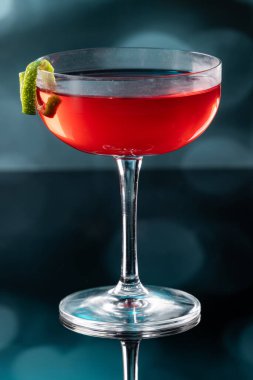 Güzel kozmopolit kokteyli limon kıvrımı ve dramatik ışıklandırmayla süslenmiş.