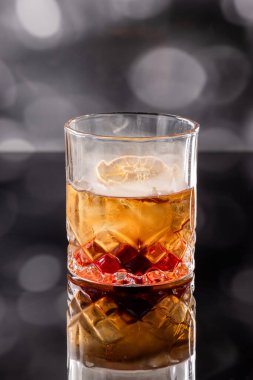 Kokteylin üstünde portakal kabuğu ve kirazla servis edilen aromatik duman. Dramatik ışıklandırma kullanımı, kokteylin dumanını ve hissini vurgular..