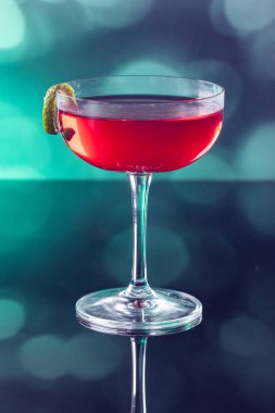 Güzel kozmopolit kokteyli limon kıvrımı ve dramatik ışıklandırmayla süslenmiş.