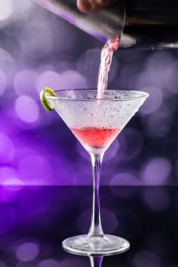 Güzel kozmopolit kokteyli limon kıvrımı ve dramatik ışıklandırmayla süslenmiş.