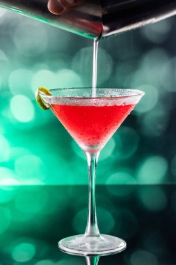 Güzel kozmopolit kokteyli limon kıvrımı ve dramatik ışıklandırmayla süslenmiş.