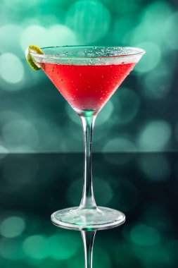 Güzel kozmopolit kokteyli limon kıvrımı ve dramatik ışıklandırmayla süslenmiş.