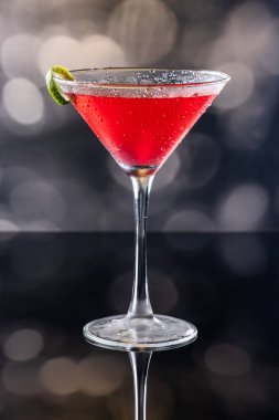 Güzel kozmopolit kokteyli limon kıvrımı ve dramatik ışıklandırmayla süslenmiş.