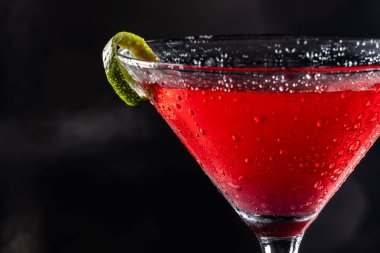 Güzel kozmopolit kokteyli limon kıvrımı ve dramatik ışıklandırmayla süslenmiş.