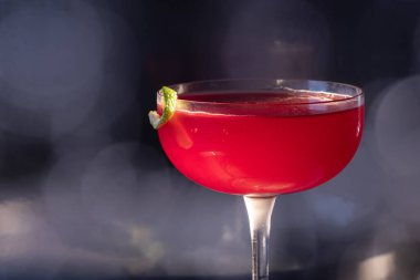 Güzel kozmopolit kokteyli limon kıvrımı ve dramatik ışıklandırmayla süslenmiş.