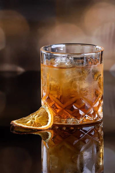 Viski kokteyli, kayalarda servis edilir. Kurumuş portakal dilimiyle süslenir. Tahta bir yüzey üzerinde çarpıcı ışıklandırmayla servis edilir..