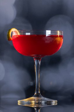 Güzel kozmopolit kokteyli limon kıvrımı ve dramatik ışıklandırmayla süslenmiş.