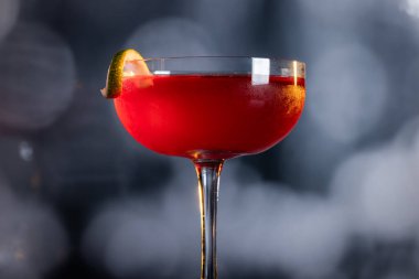 Güzel kozmopolit kokteyli limon kıvrımı ve dramatik ışıklandırmayla süslenmiş.