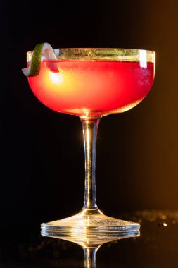 Güzel kozmopolit kokteyli limon kıvrımı ve dramatik ışıklandırmayla süslenmiş.