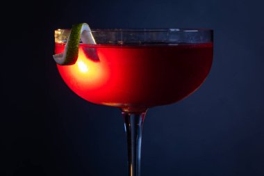 Güzel kozmopolit kokteyli limon kıvrımı ve dramatik ışıklandırmayla süslenmiş.