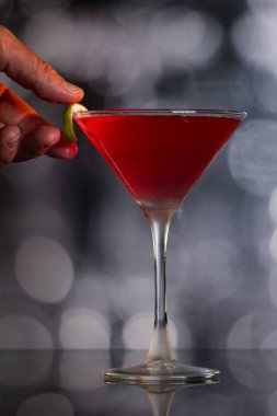 Güzel kozmopolit kokteyli limon kıvrımı ve dramatik ışıklandırmayla süslenmiş.