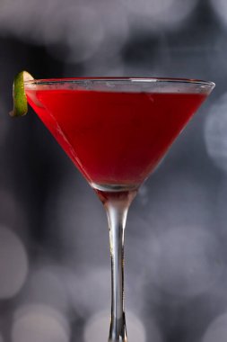 Güzel kozmopolit kokteyli limon kıvrımı ve dramatik ışıklandırmayla süslenmiş.