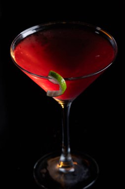 Güzel kozmopolit kokteyli limon kıvrımı ve dramatik ışıklandırmayla süslenmiş.
