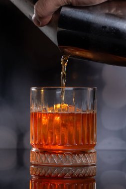 Büyük yuvarlak bir buz topunun üzerine viski kokteyli döküyorum.