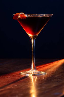 Siyah Martini, sıcak bir tonda, turuncu bir kıvrımla süslenmiş güçlü bir ışıktan.