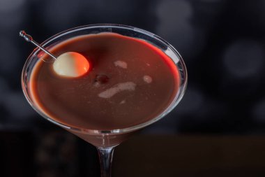 Çikolata karışımının yakın plan bir profili coupe bardakta, gümüş bir kazmada siyah ve beyaz bir çikolata mantarı ile süslenmiş, yumuşak, profesyonel bir bokeh arka planda..