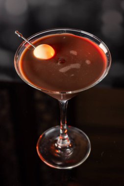 Çikolata karışımının yakın plan bir profili coupe bardakta, gümüş bir kazmada siyah ve beyaz bir çikolata mantarı ile süslenmiş, yumuşak, profesyonel bir bokeh arka planda..