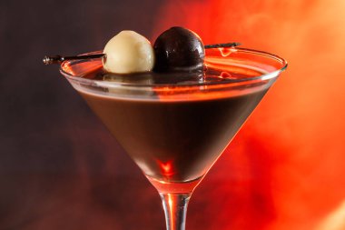 Siyah ve beyaz trüf mantarlarıyla süslenmiş, atmosferik duman ve sıcak, kırsal ahşap bir yüzey üzerinde parlayan ışık içeren zengin bir çikolata kokteylinin profesyonel yan profil çekimi..