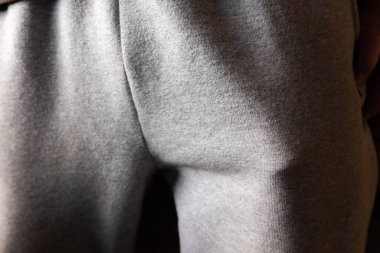 Cebinde komik bir nesne. Açık gri kumaş pantolon giyen, göze çarpan bir şekle odaklanan ve cebin içinde koyu bir arka plana doğru şişen bir kişinin detaylı görüntüsü..