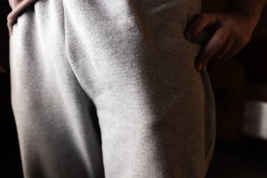 Cebinde komik bir nesne. Açık gri kumaş pantolon giyen, göze çarpan bir şekle odaklanan ve cebin içinde koyu bir arka plana doğru şişen bir kişinin detaylı görüntüsü..