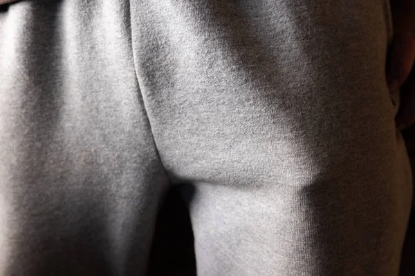 Cebinde komik bir nesne. Açık gri kumaş pantolon giyen, göze çarpan bir şekle odaklanan ve cebin içinde koyu bir arka plana doğru şişen bir kişinin detaylı görüntüsü..