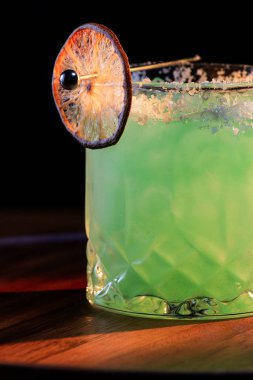 Koyu arkaplanda kurutulmuş kireç tekeri olan tuzlu bir margarita.