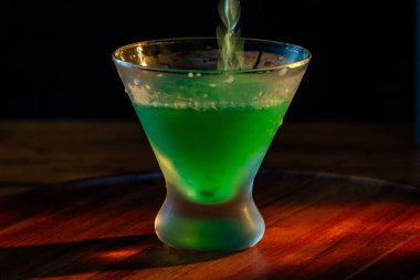 Sönük bir martini bardağına parlak yeşil bir martini dolduruyorum.