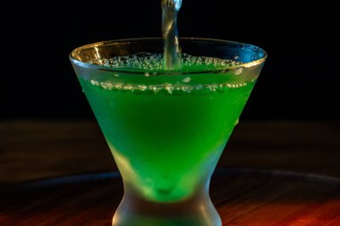 Sönük bir martini bardağına parlak yeşil bir martini dolduruyorum.