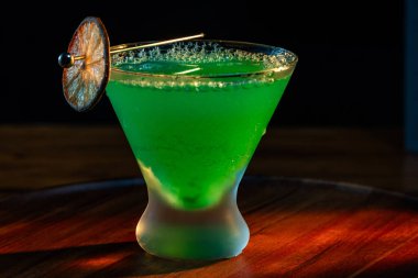 Ahşap tepside canlı renkte, sert dramatik ışıklandırmalı klasik yeşil içecek.