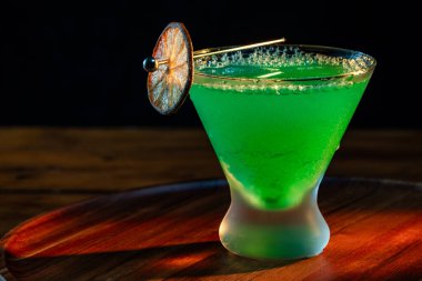 Ahşap tepside canlı renkte, sert dramatik ışıklandırmalı klasik yeşil içecek.