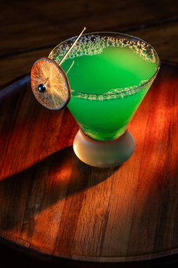 Ahşap tepside canlı renkte, sert dramatik ışıklandırmalı klasik yeşil içecek.